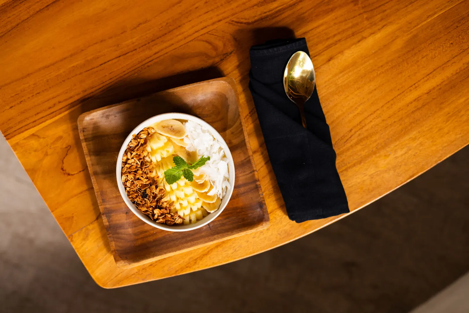 Smoothie bowl with granola and fruit on a wooden tray