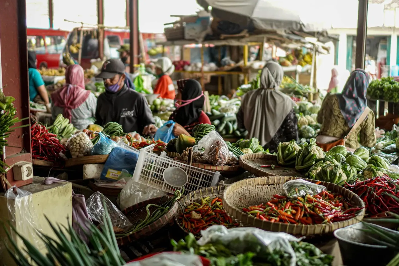 Local market stalls with baskets of chillies and vegetables, women vendors in headscarves